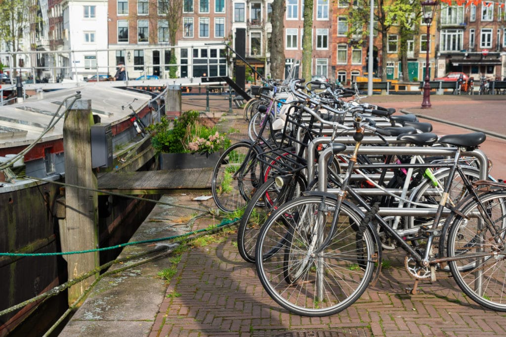 Row of bicycles standing next to canal in Amsterdam, Netherlands